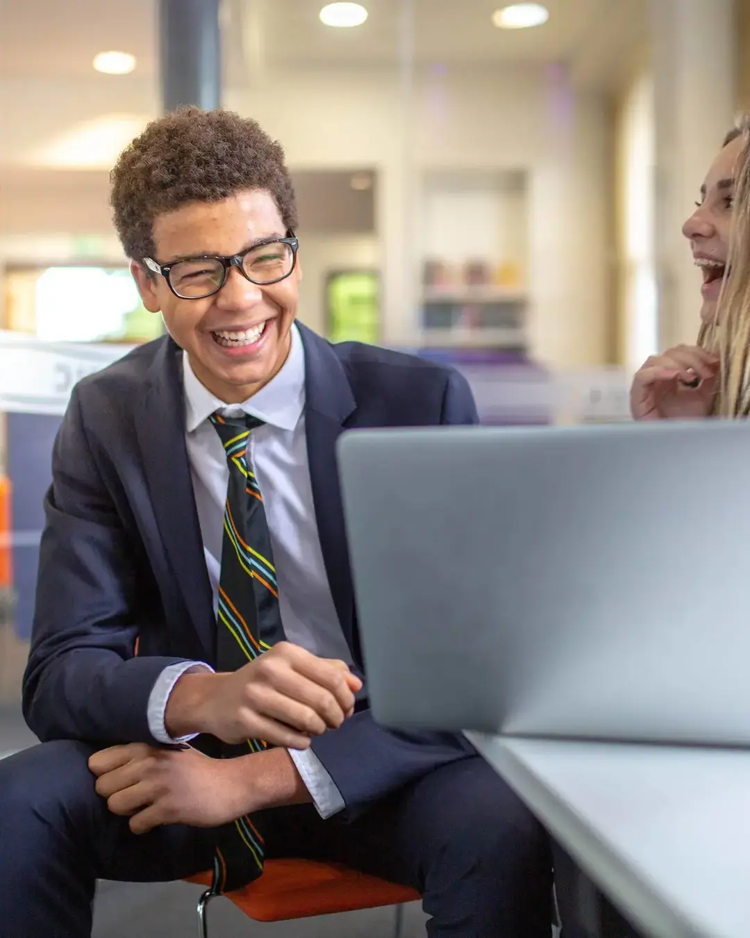 Students laughing while doing schoolwork on laptop